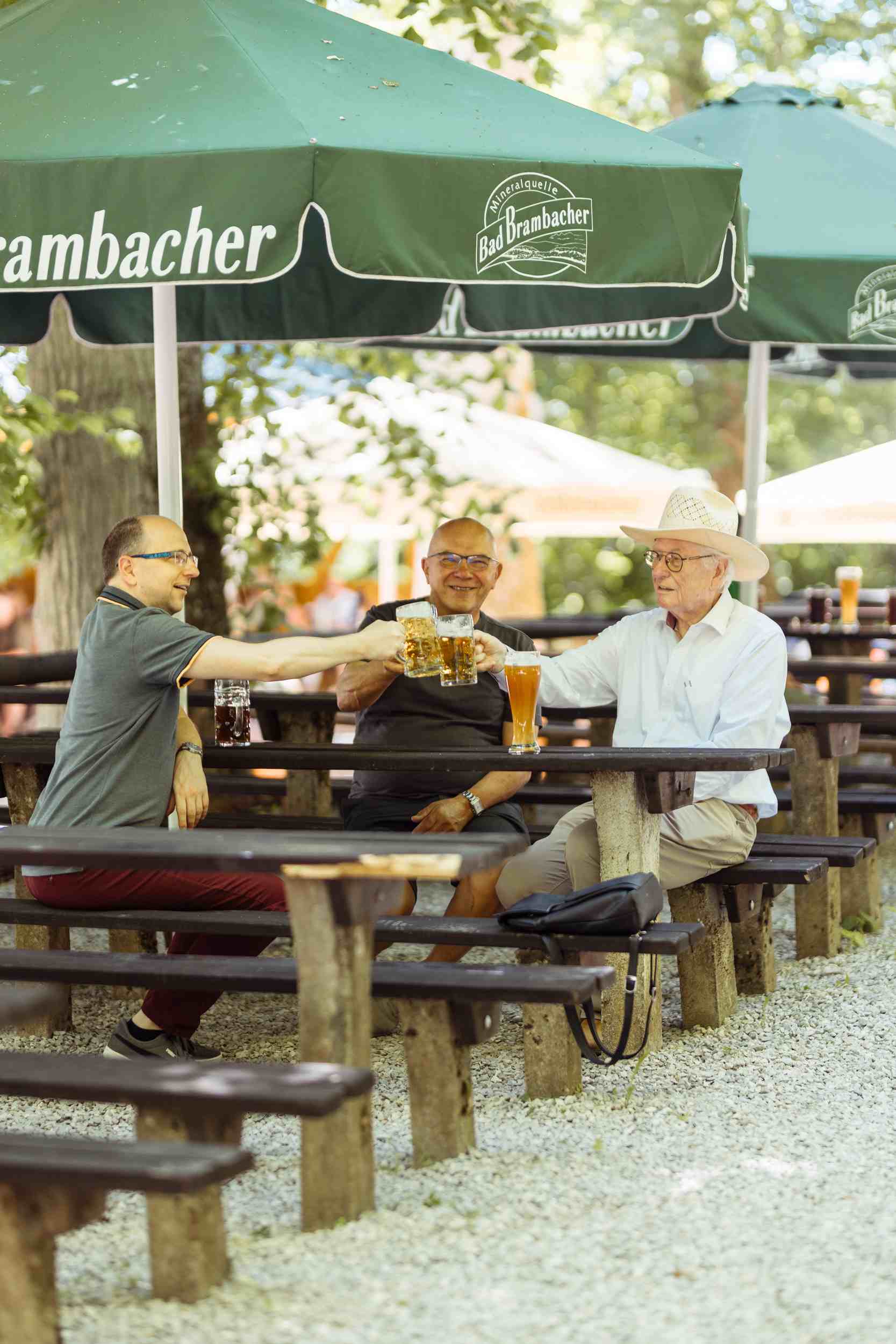 Drei Gäste stoßen mit Biergläsern an
